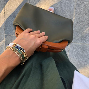 yeşil çantalı kadının bileklerinde doğal taşlardan doğal incilerden tasarlanmış bileklikler kombinlenmiş