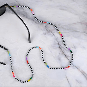 Beyaz mermer üzerinde renkli boncuklu, silikon tutacaklık üzerinde "Serial Chiller" yazan gözlük zinciri