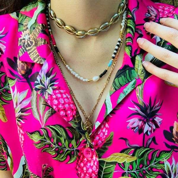 Çiçek desenli, pembe gömlekli kadının üzerinde, renkli doğal incili ve doğal boncuklu choker kolye.