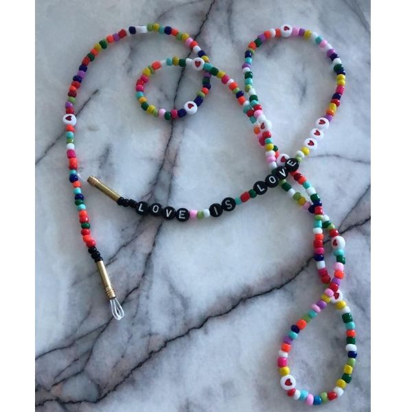 Beyaz mermer üzerinde, Love is Love yazan, renkli ve doğal boncuklu, uzun gözlük ipi.