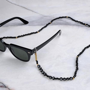 Beyaz mermer üzerinde siyah boncuklardan oluşan, silikon tutacaklı üzerinde "Heart of Gold" yazan gözlük zinciri